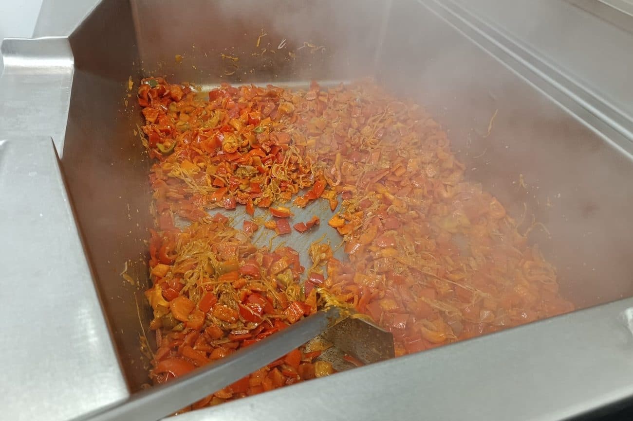 Poivrons et tomates mijotant dans la sauteuse basculante